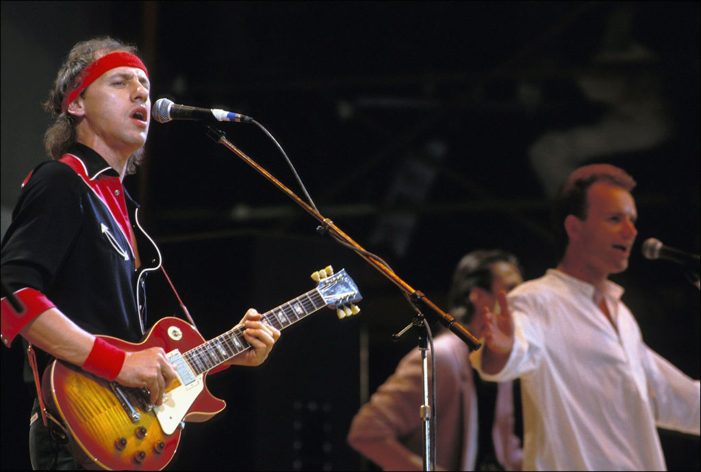 Mark Knopfler a Dire Straits énekese, valamint Sting (a háttérben) ad koncertet a Wenbley stadionban 1985-ben a Live Aid rendezvényén. Többek között az itt használt gitár is árverésre kerül (Fotó Georges De Keerle/Getty Images)