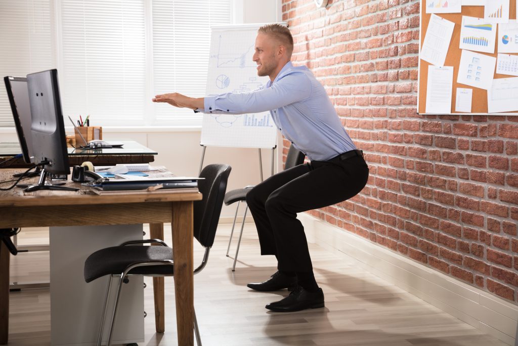 Happy Businessman Doing Exercise In Front Of Computer At Office